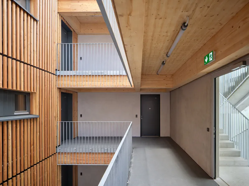 Interior atrium with exposed timber ceiling, metal railings across three levels and skylight above
