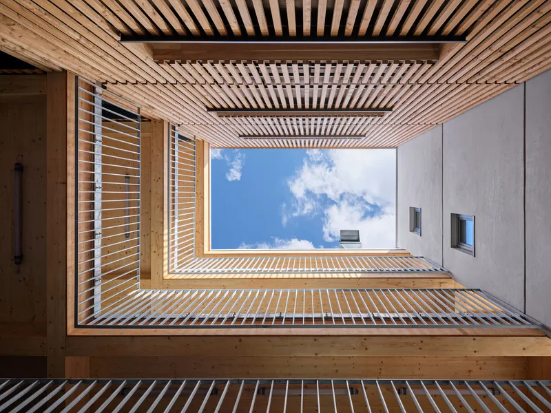 View up through timber louvered courtyard framing blue sky with white clouds