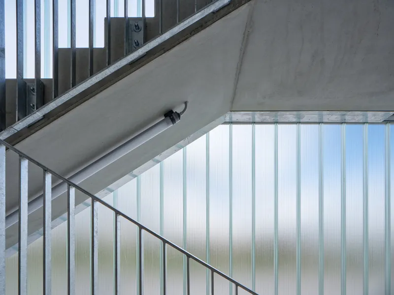 Stairwell with translucent corrugated paneling and concrete soffit viewed from below