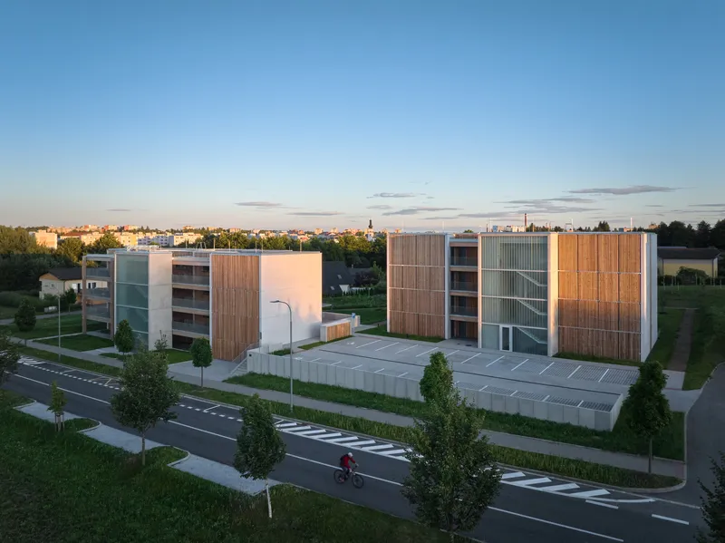 Aerial view of two residential blocks with timber screens and parking lot at golden hour
