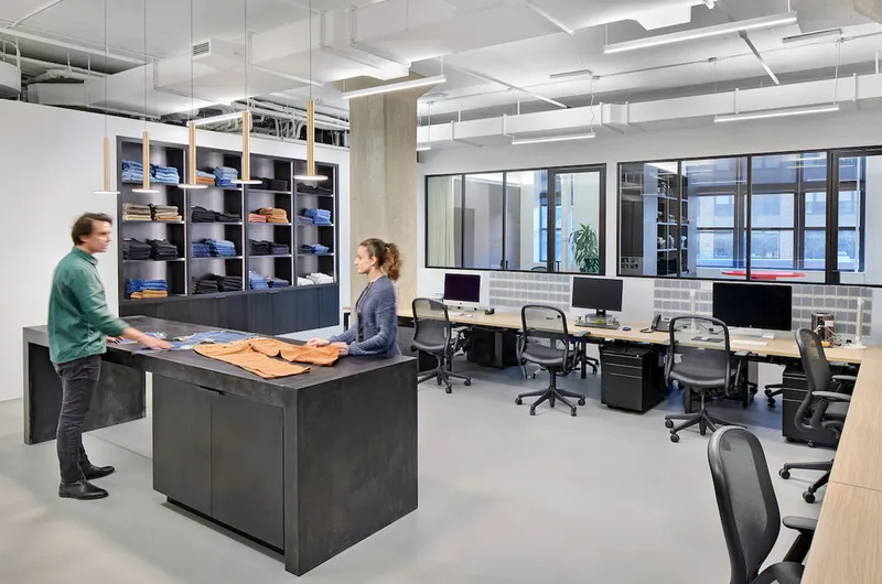 Workspace with dark millwork storage wall and two people standing at a central work counter