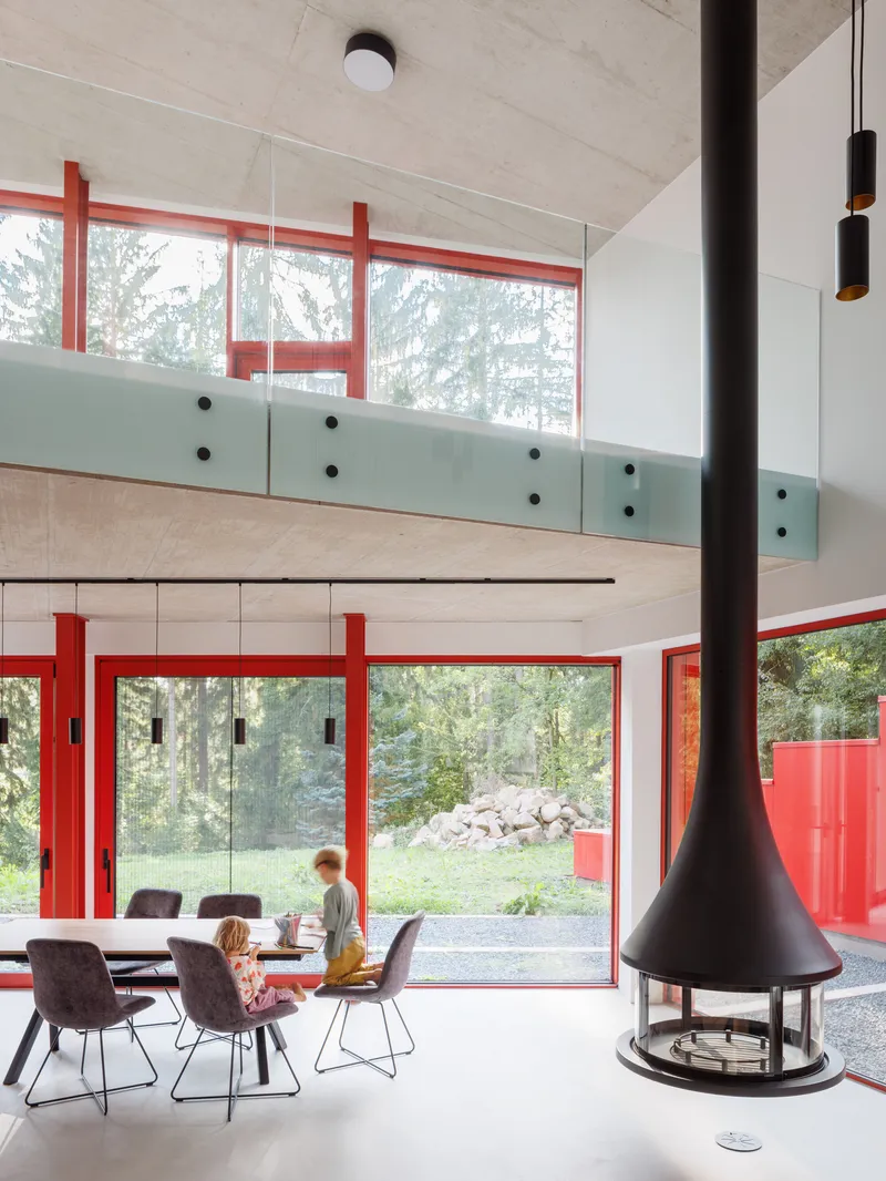 Double-height dining space with suspended fireplace, pale wood ceiling and mezzanine with glass balustrade