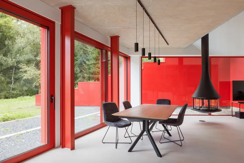 Dining area with red glazing frames, suspended fireplace and cluster of black pendant lights