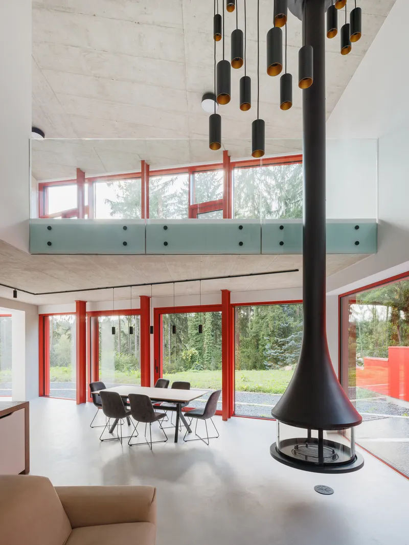 Double-height living space with suspended fireplace, pendant lights, and mezzanine with perforated green railing