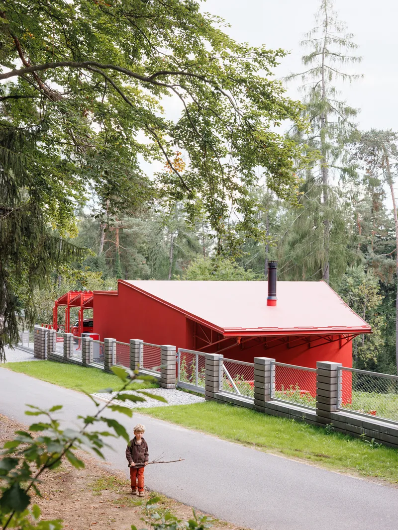Side elevation showing the corrugated metal fence and pitched roof with a child on the path