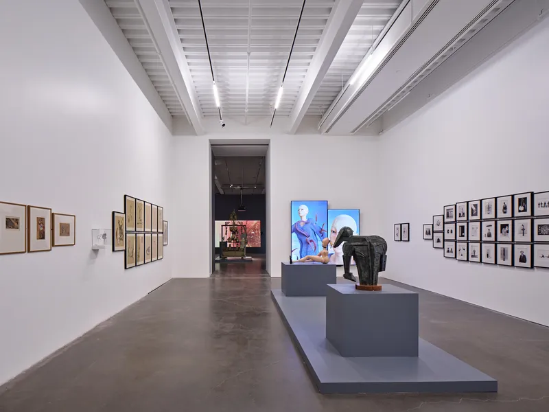 Gallery space with polished concrete floor, framed works on walls, and sculpture on grey plinth