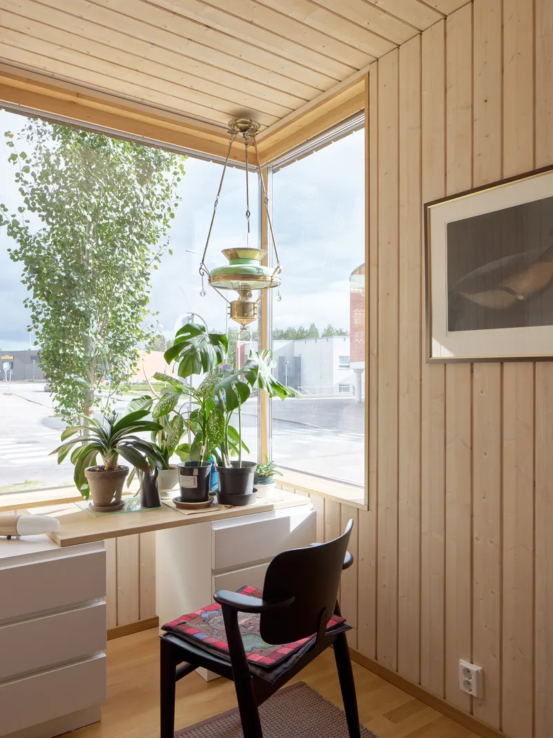 Corner workstation with vertical timber cladding and a row of potted plants on the sill