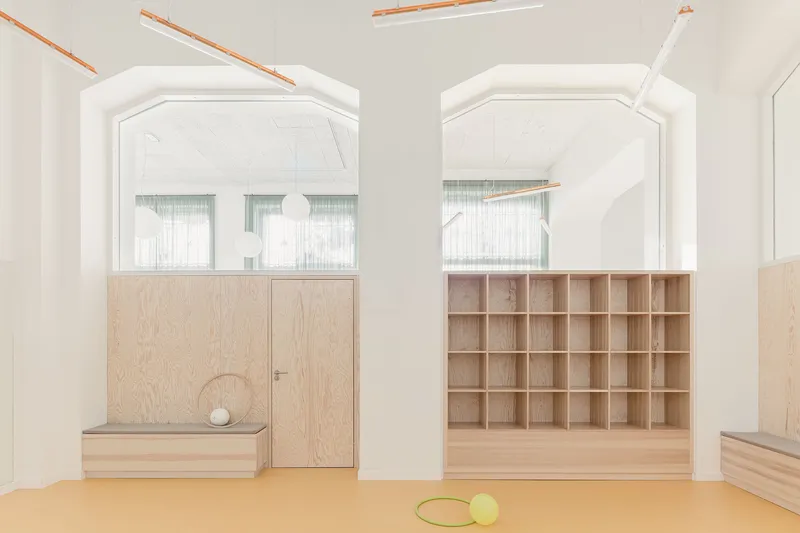Interior room with arched white portals framing plywood doors and cubby shelving with orange linear lighting above
