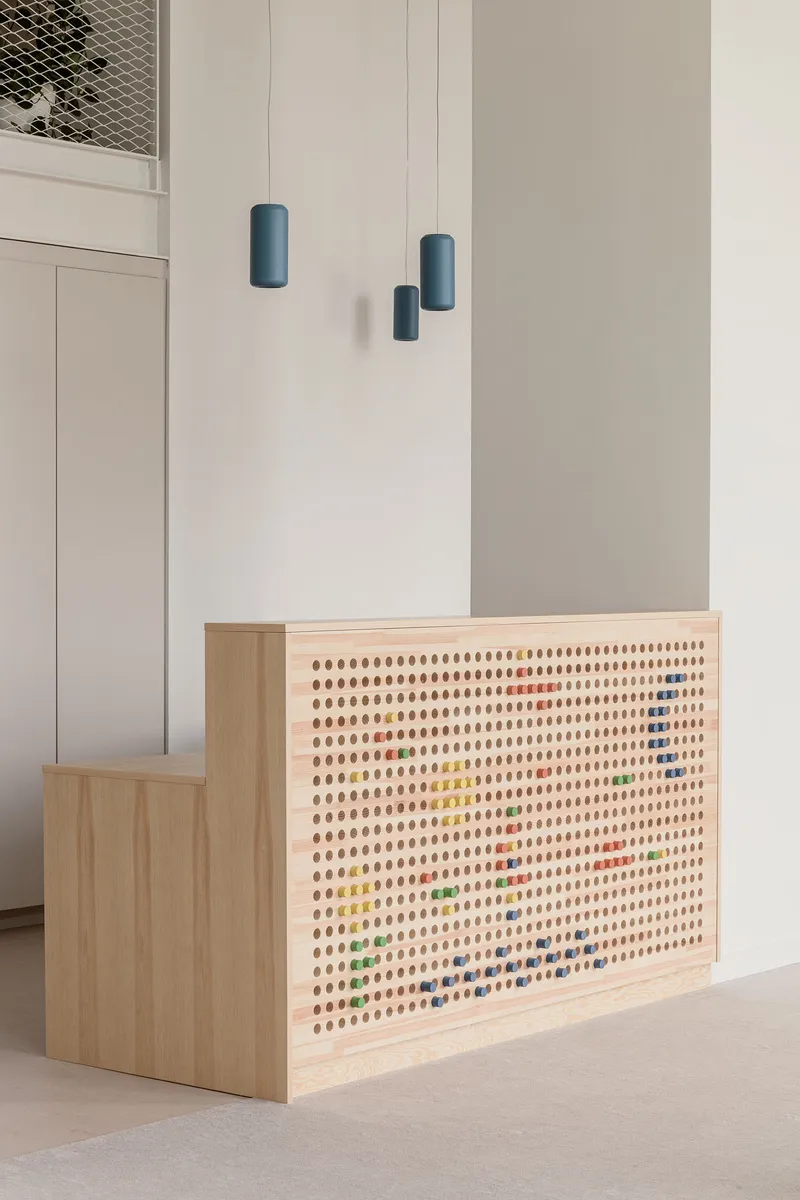 Close-up of pegboard counter with colorful pegs beneath three cylindrical blue pendant fixtures
