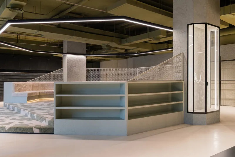 Detail of tiered display shelving adjacent to the geometric patterned floor and illuminated concrete column