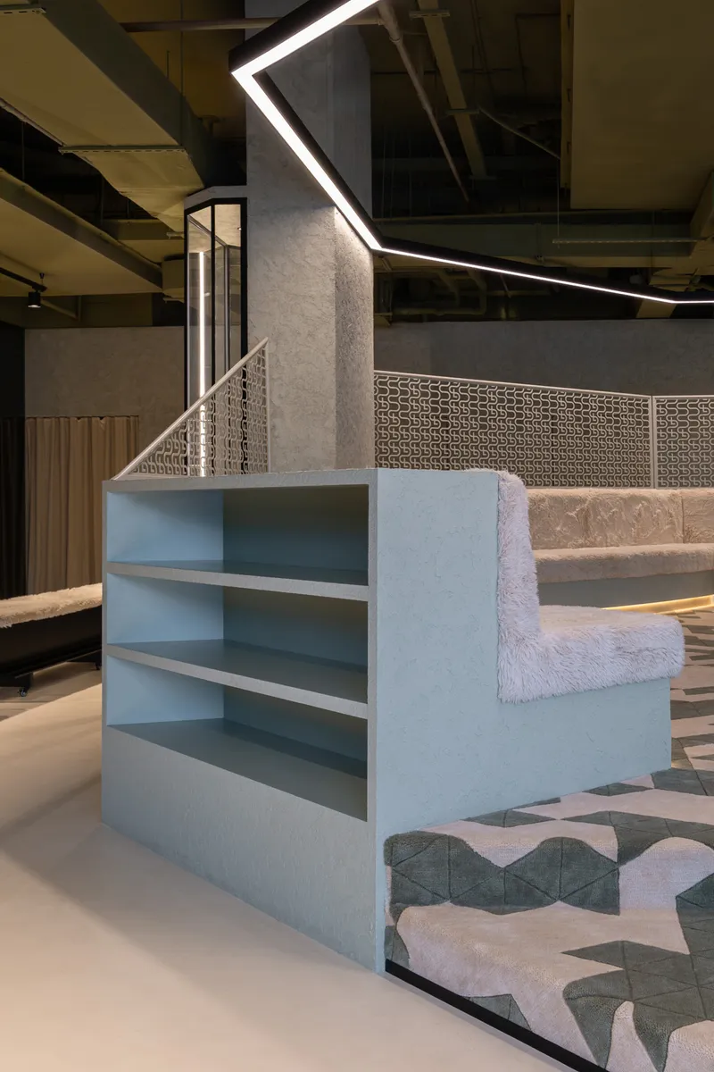 Blue-painted stepped shelving unit beside a patterned tile floor under exposed ceiling structure