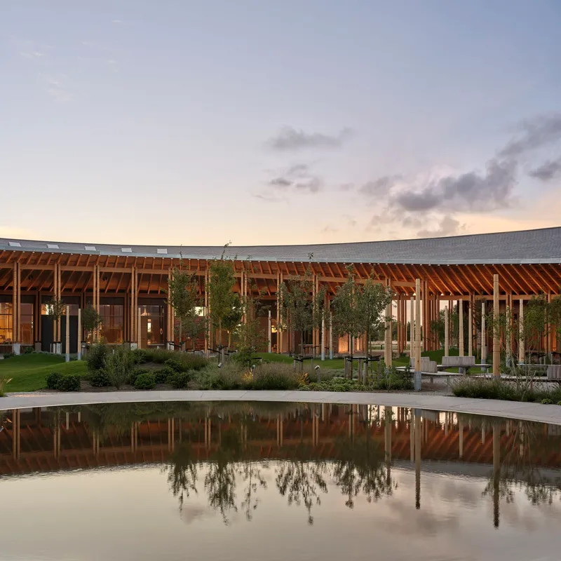 Timber-framed facade with central courtyard and reflecting pool at dusk