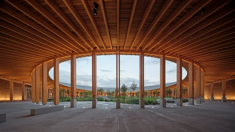 Central courtyard under a radial timber ceiling with curved glazing overlooking the landscape