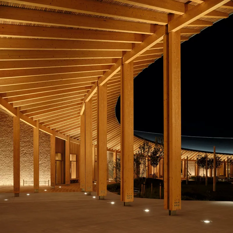Covered colonnade with exposed timber rafters and floor-mounted uplights at night