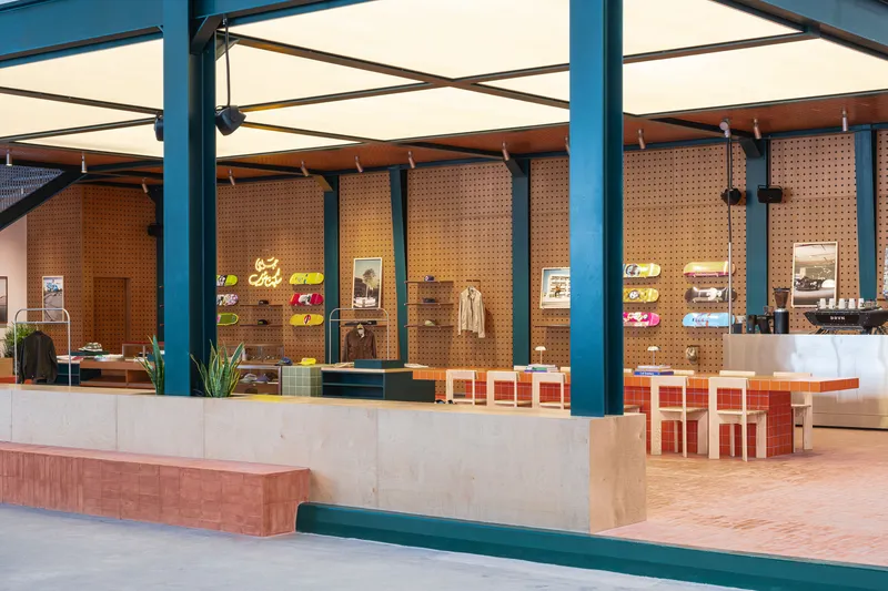 Retail counter with pegboard display walls and tiled seating under exposed steel beams and skylights