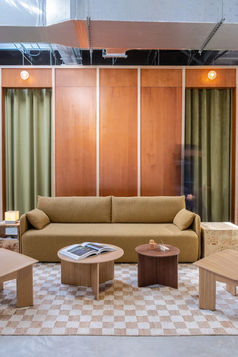 Seating alcove with plywood panels, olive curtains and checkered floor beneath exposed mechanical ceiling