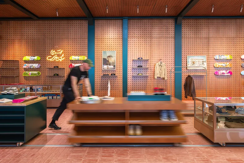 Perforated pegboard wall with blue steel columns displaying merchandise and a person walking past