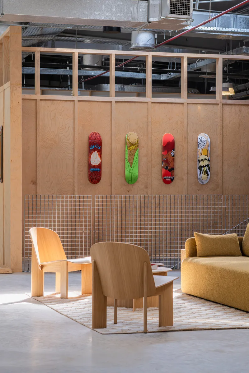 Plywood partition with four skateboards mounted above a mosaic tile wainscot and exposed ductwork overhead