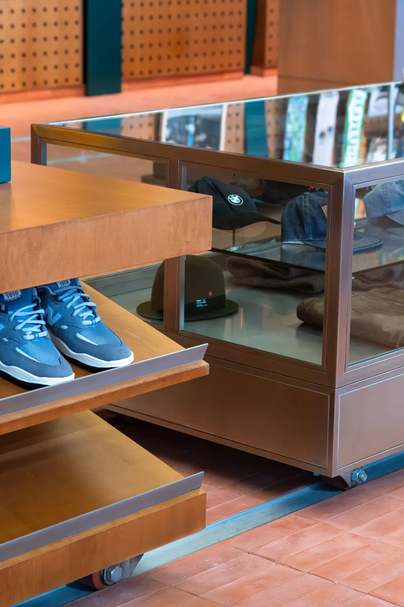 Mobile display units with glass shelves and plywood platforms on casters in terracotta tiled space