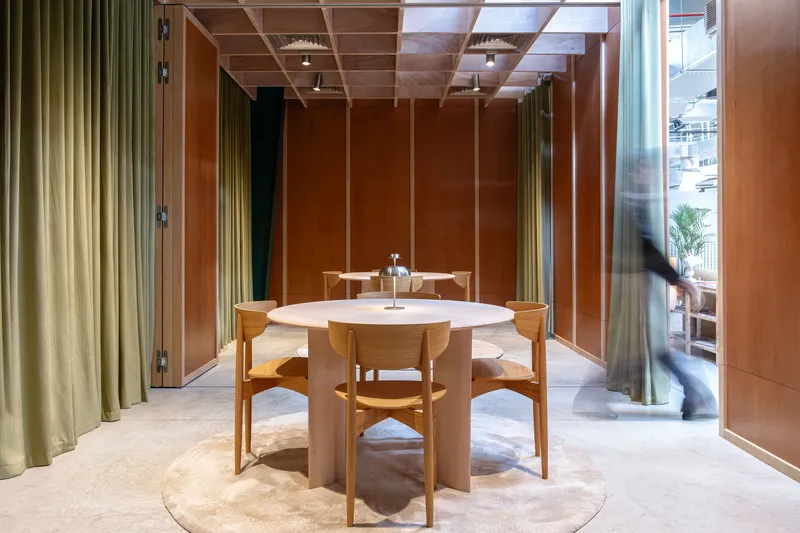 Private dining room with timber coffered ceiling and olive drapery framing a passing figure