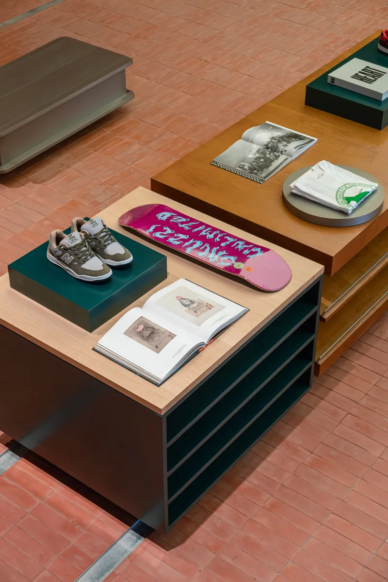 Display table with timber top and green metal base on terracotta tile flooring showing merchandise and publications