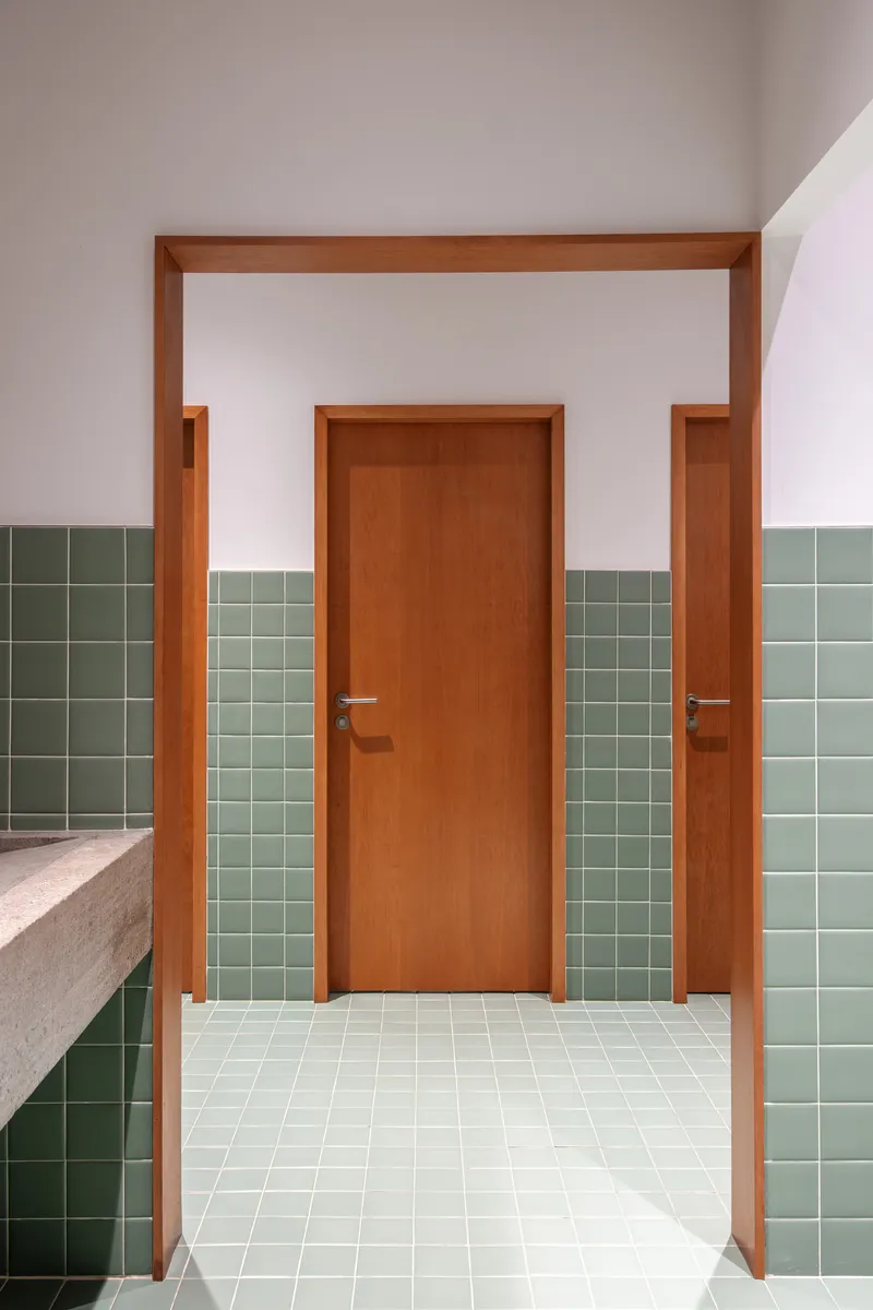 Hallway with timber door framed by sage green tile wainscoting and cream terrazzo countertop