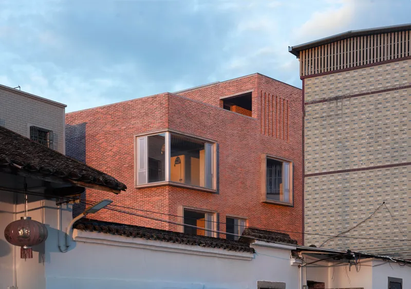Red brick facade with protruding bay window and angled brickwork details at dusk