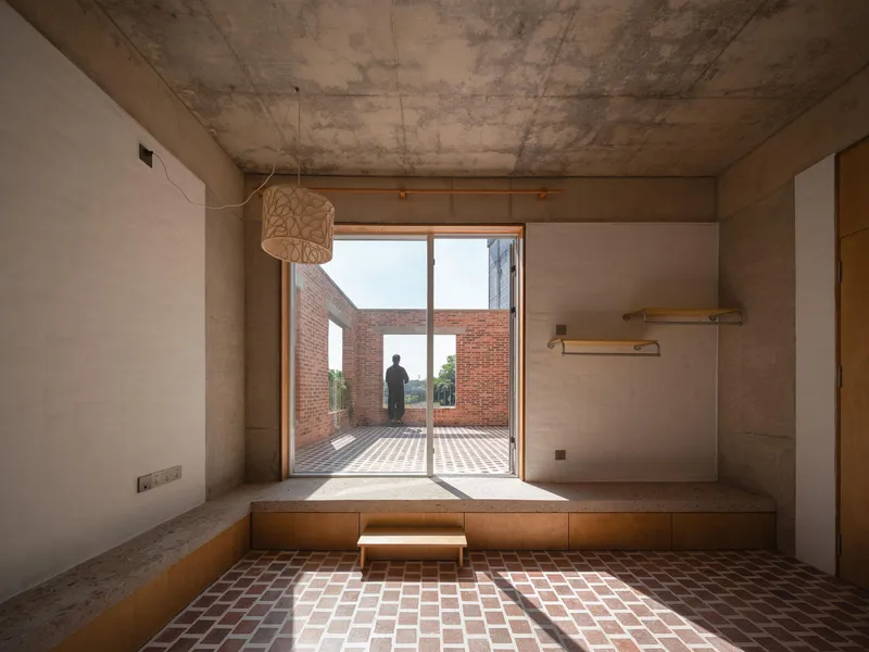 Interior room with timber bench and doorway framing a person on the terrace beyond