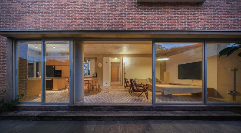 Glazed rear facade opening to interior living spaces illuminated at dusk