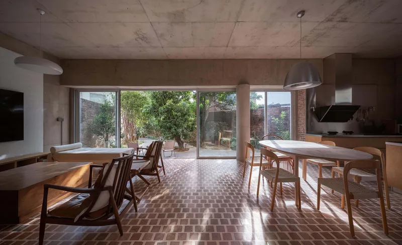 Open plan dining and living space with patterned tile floor and full-height glazing opening to a planted courtyard