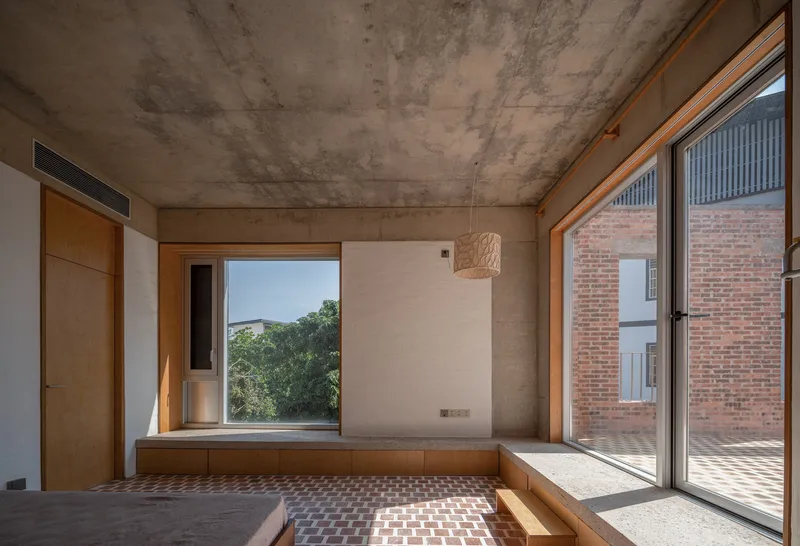 Built-in timber window seat with view to courtyard and exposed concrete soffit casting geometric shadows