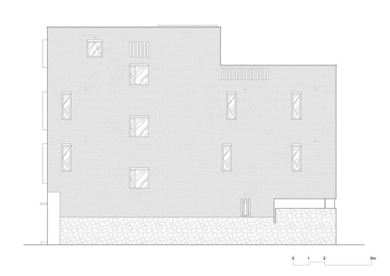 Elevation drawing showing a textured wall with scattered rectangular openings and a gravel base