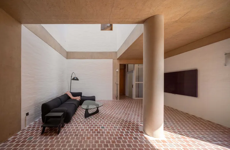 Living room with patterned terracotta floor tiles, cylindrical column, and clerestory skylight above