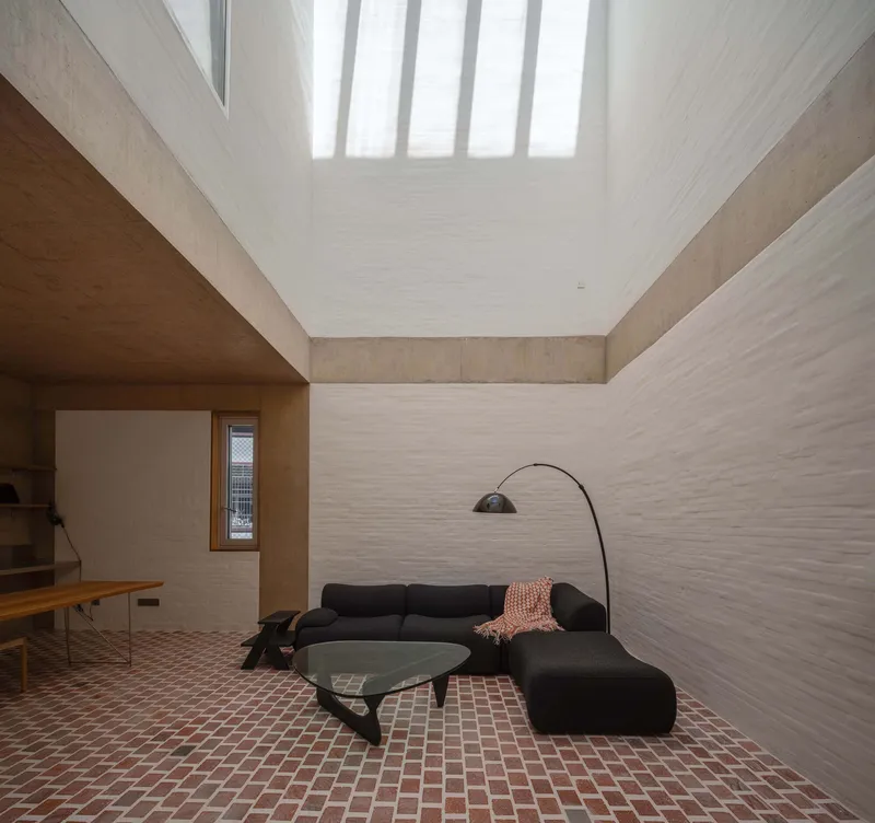 Interior courtyard space with terracotta tile floor and vertical skylight slats diffusing natural light