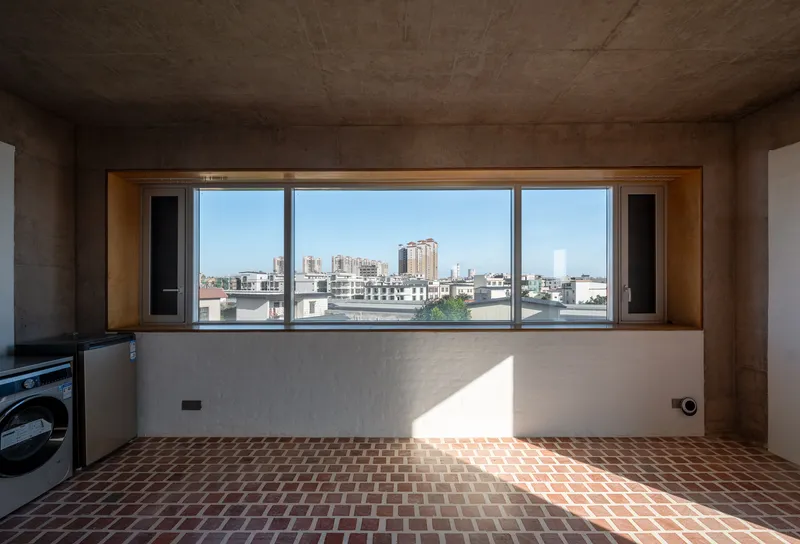 Interior space with timber-framed window overlooking the city and red brick herringbone floor