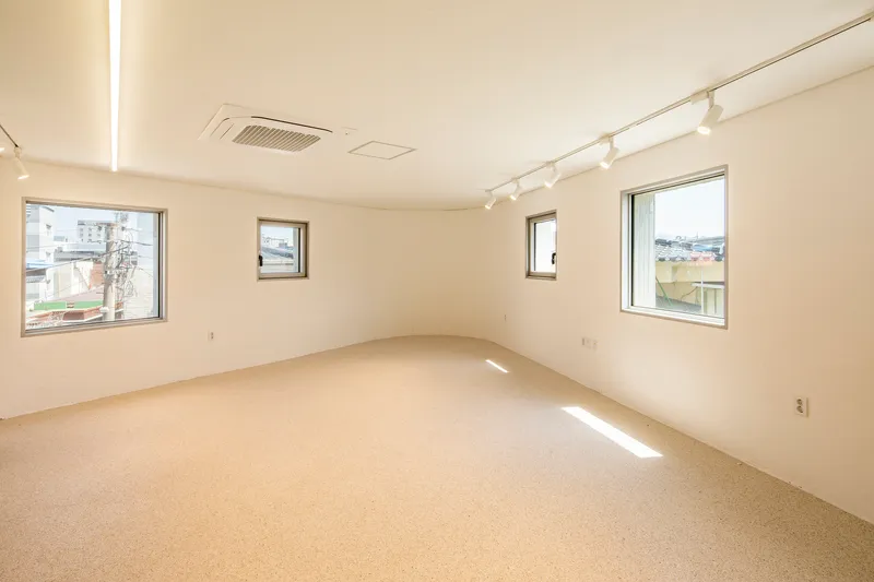 Interior room with terrazzo flooring and three square windows framing views of the surrounding neighborhood
