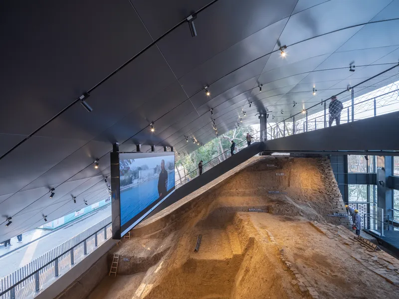 Interior view of excavated earth ramp beneath a sloped metal panel ceiling with track lighting
