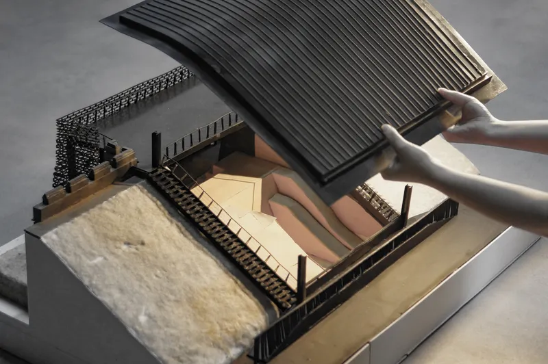 Cutaway model view showing interior courtyard spaces beneath a lifted ribbed roof section