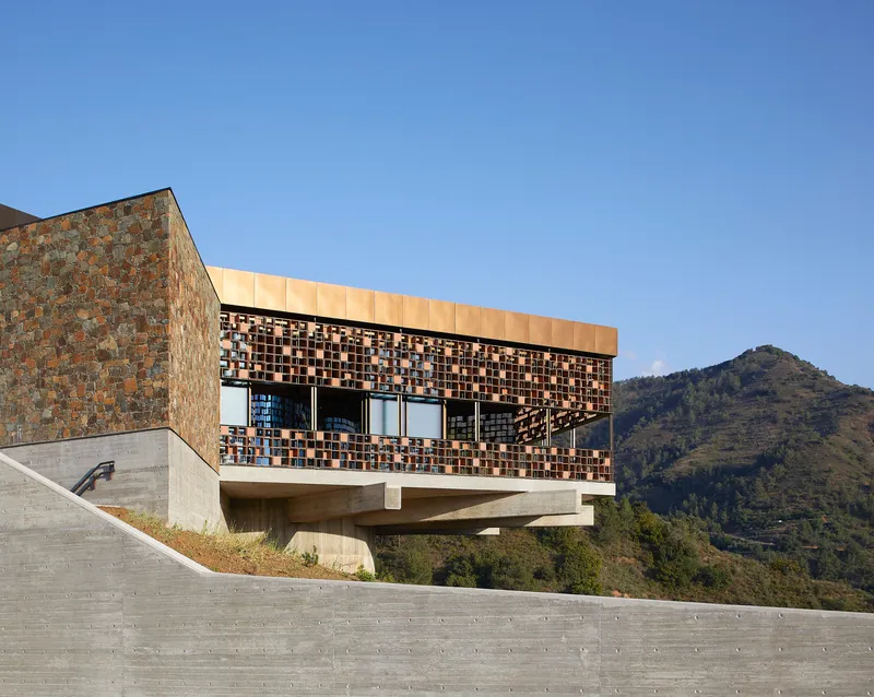 Upper volume with patterned tile screen and ribbon windows overlooking mountain terrain in daylight