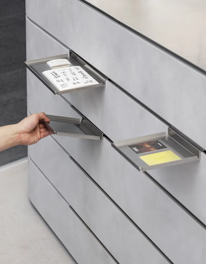 Hand pulling open recessed drawer with paper inserts in ribbed wall panel system
