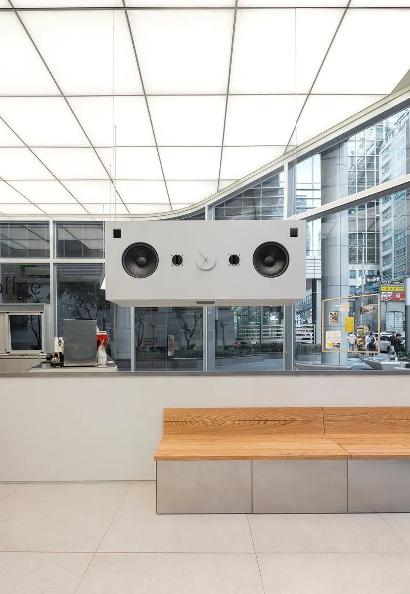 Service counter with integrated speaker grilles beneath a curved backlit ceiling grid