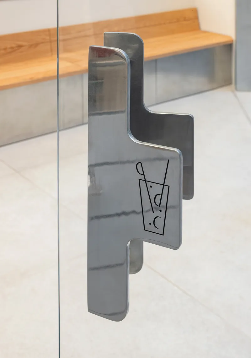 Steel door pull with etched beverage icon mounted on glass panel