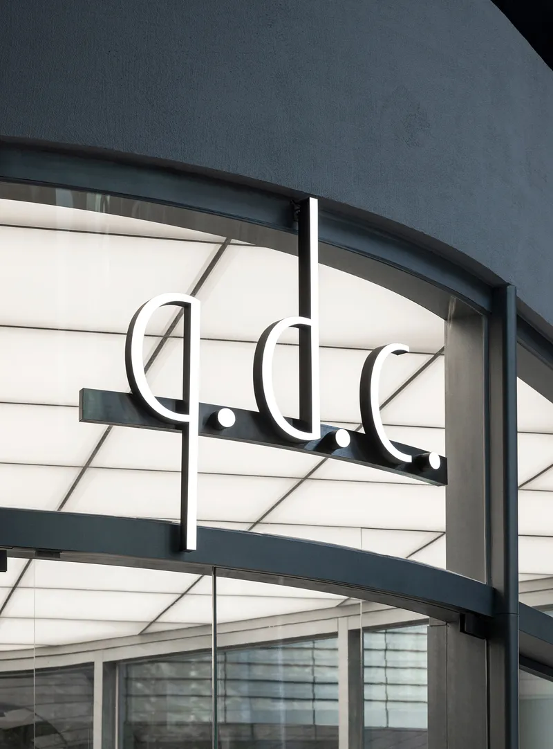 Illuminated signage and horizontal banding detail on the curved storefront canopy
