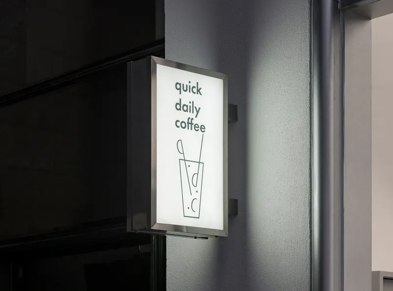 Backlit wall-mounted signage panel against a textured gray exterior wall