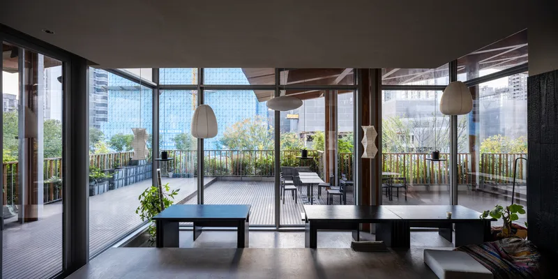 Interior living space with full-height glazing opening onto planted terrace with city towers beyond