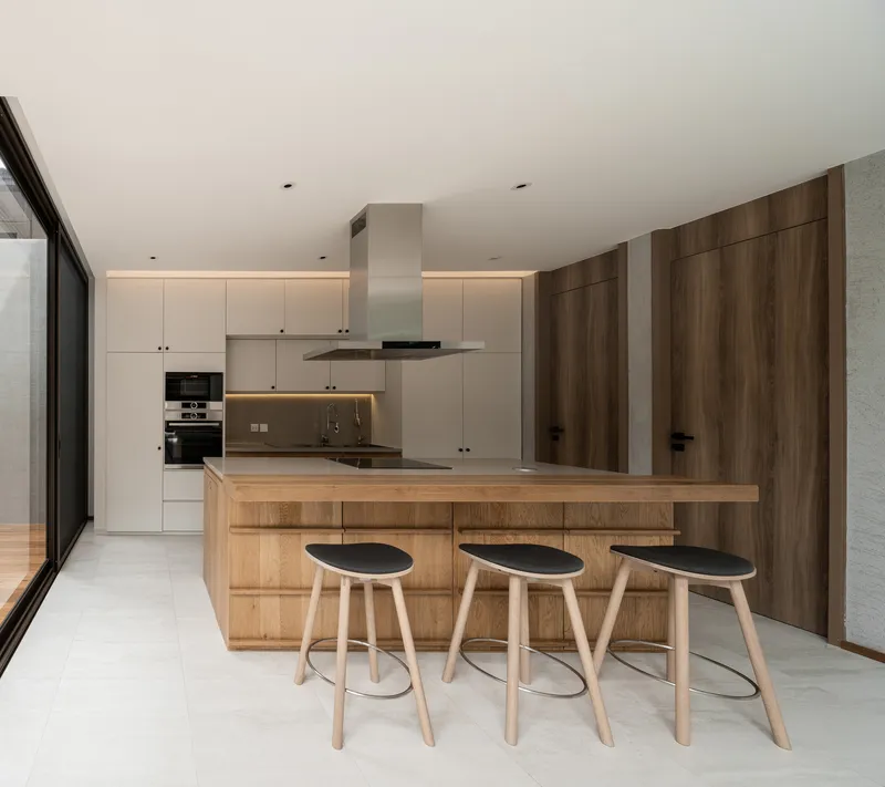 Kitchen with timber island, three bar stools, and white cabinetry with strip lighting