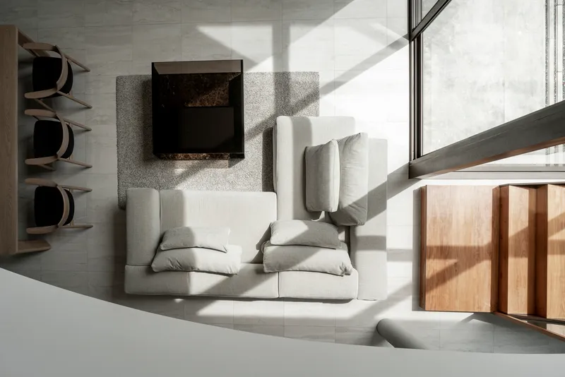 Top-down view of living area with white upholstered seating in angular afternoon sunlight