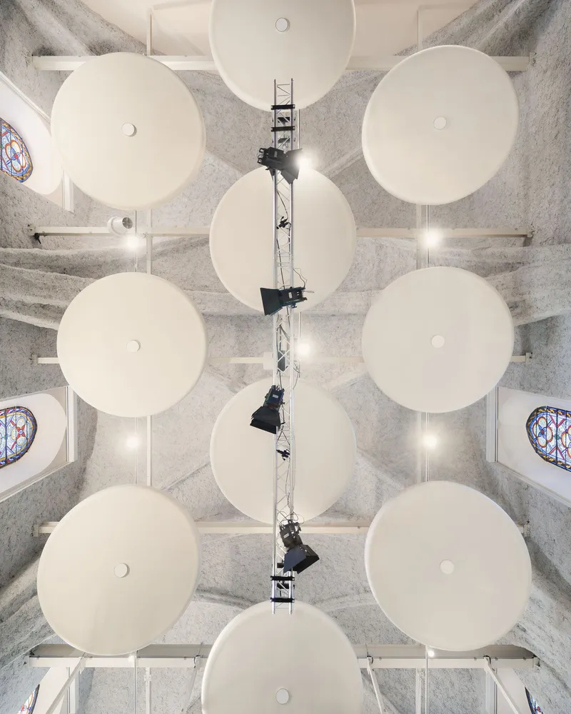 Overhead view of nine white circular acoustic panels arranged in a grid beneath a lighting rig