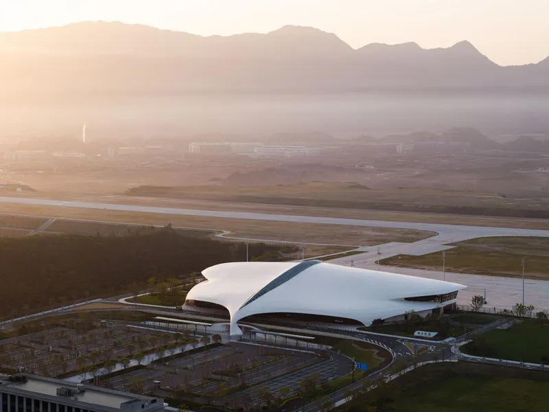 Elevated view of the building beside a river with mountains and morning mist in the distance