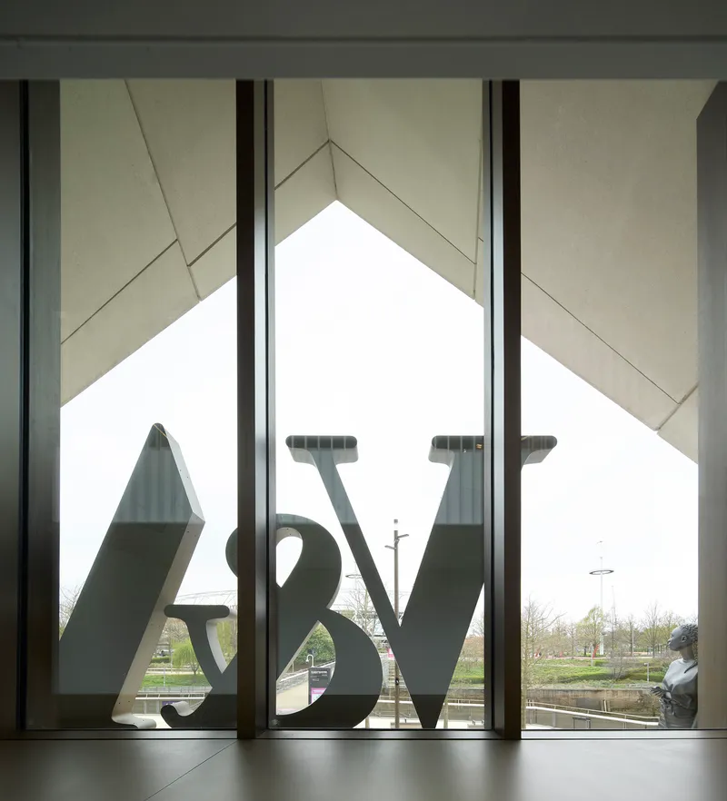 Interior view through the triangular window showing the sculpture logo silhouetted against pale sky